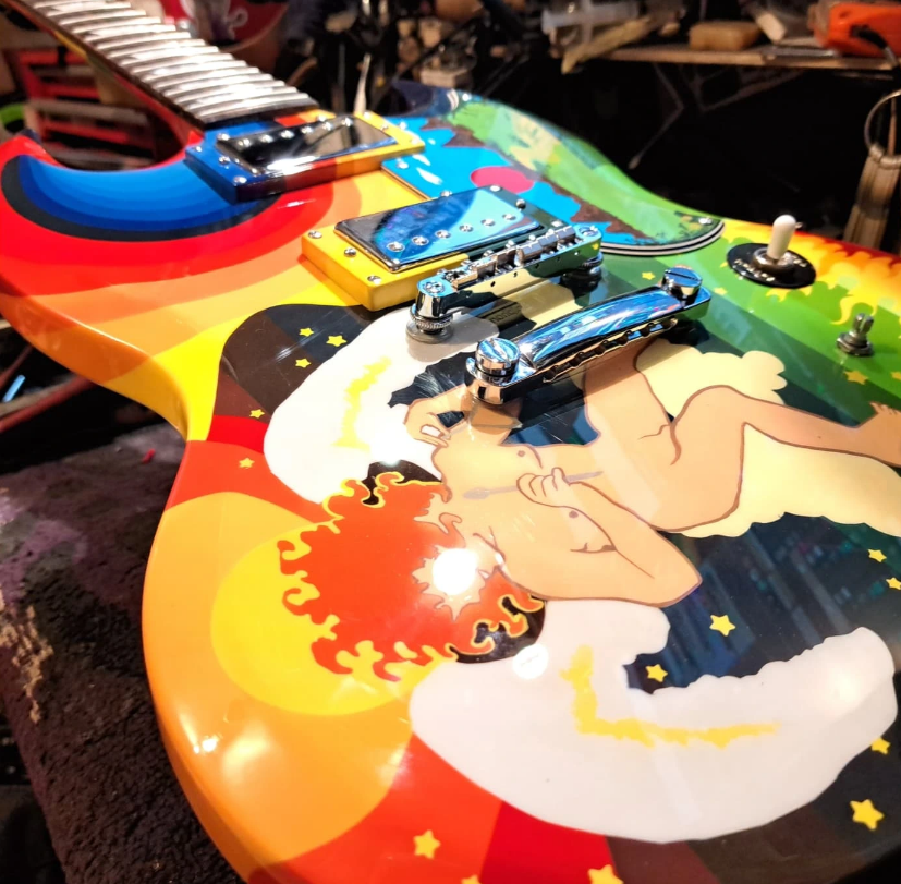A close-up view of a colorful electric guitar featuring a vibrant, psychedelic design. The guitar's body is adorned with a...